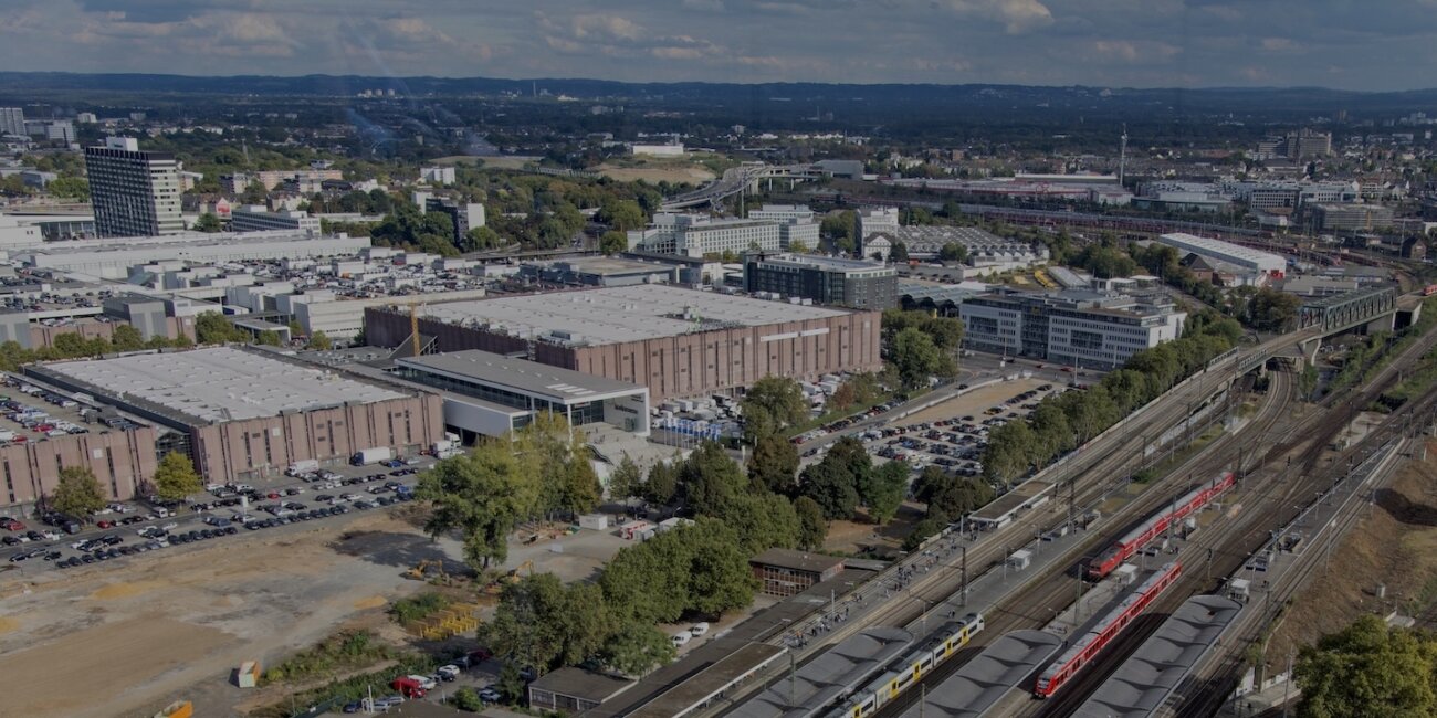 Luftbild von den Messehallen in Köln, im Vordergrund der Bahnhofe Köln Deutz Messe in dem mehrere Züge stehen