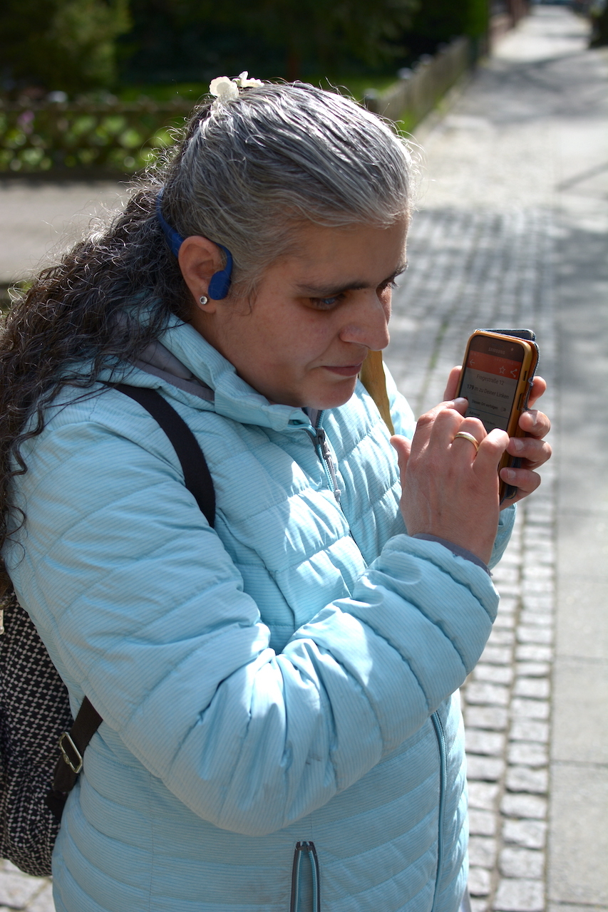 Seitliche Aufnahme einer Frau, die ein Smartphone hält und konzentriert zuhört